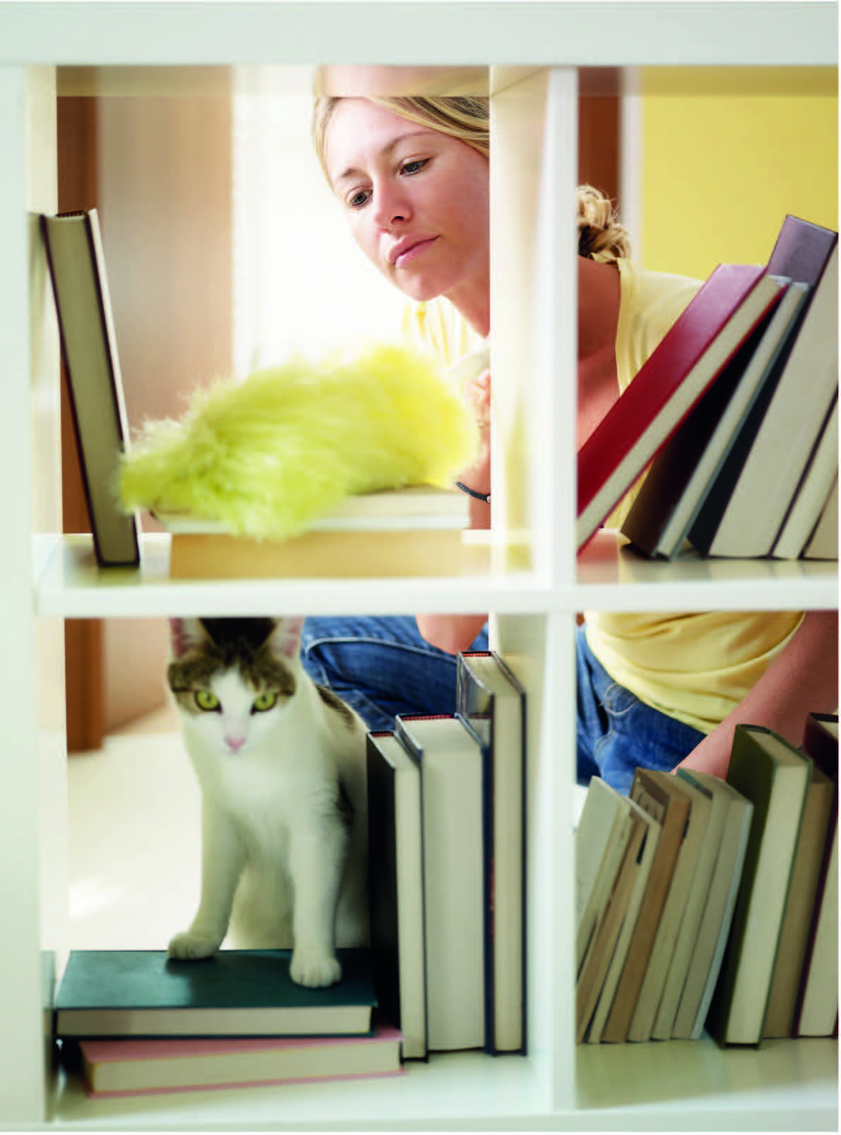 Femme rangeant une bibliothèque lors d’un ménage de printemps pour harmoniser son intérieur.
