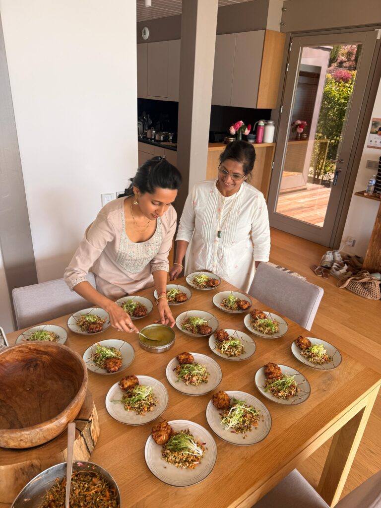 Arpitha Savale prépare plusieurs assiettes sur une table, aux côtés d’une autre femme.
